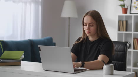 Freiberuflerin-Arbeitet-Zu-Hause-Mit-Laptop-Und-Tippt-Text-Auf-Der-Tastatur-Des-Laptops.-Büroplatz-Im-Wohnzimmer.-Mittleres-Porträt-Einer-Frau